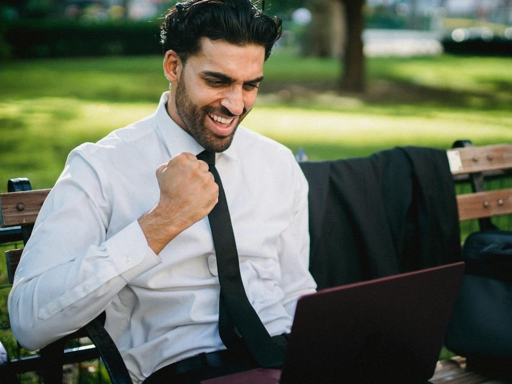 Pessoa comemorando com os braços levantados, representando a celebração de conquistas e resultados.