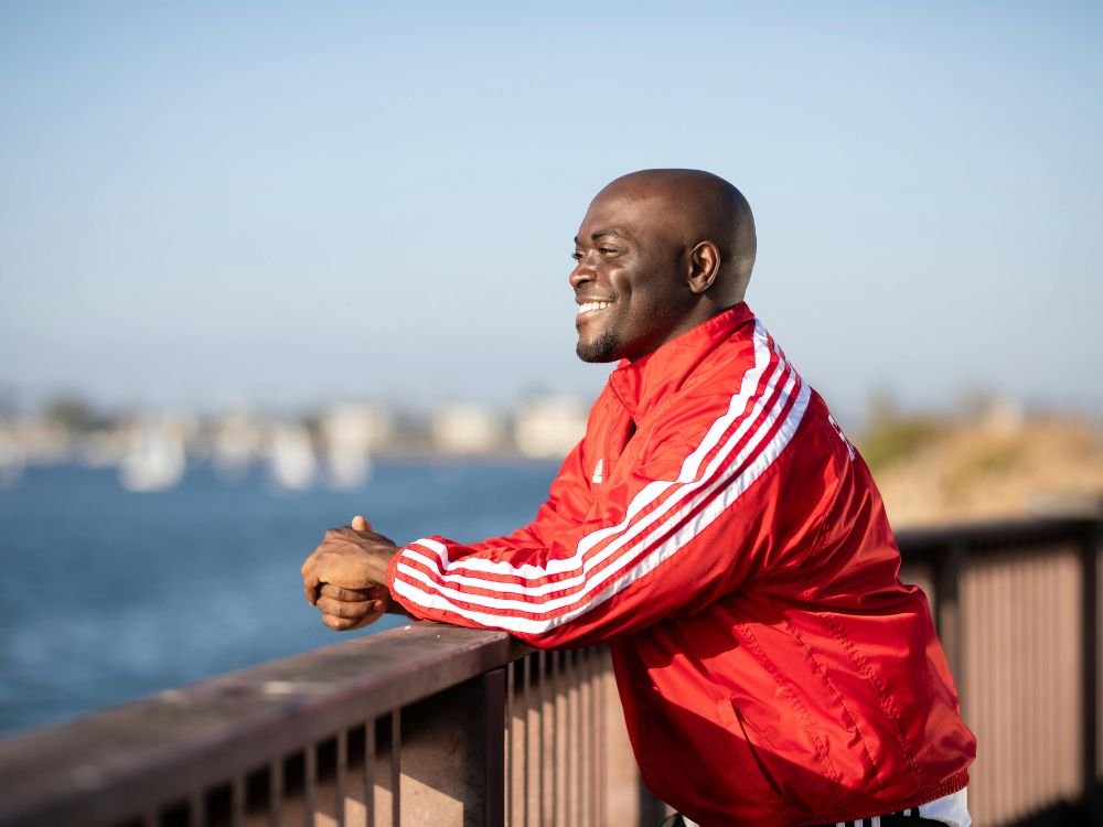 Homem sorrindo olhando para o mar, simbolizando superação e confiança no crescimento pessoal