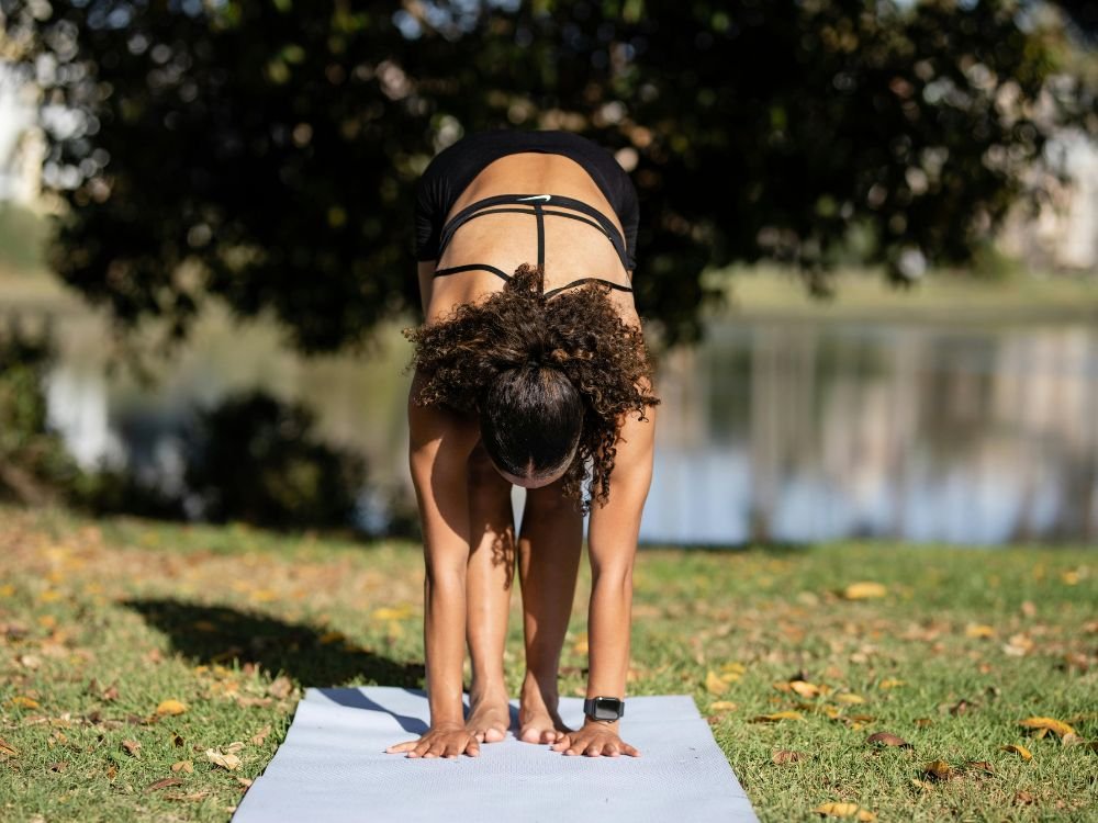 Mulher alongando-se ao nascer do sol, simbolizando uma rotina matinal poderosa e inspiradora.