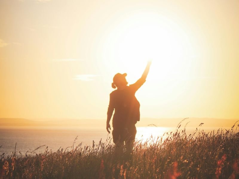 Pessoa observando o nascer do sol no topo da montanha, representando o início da transformação pessoal ao mudar o mindset.